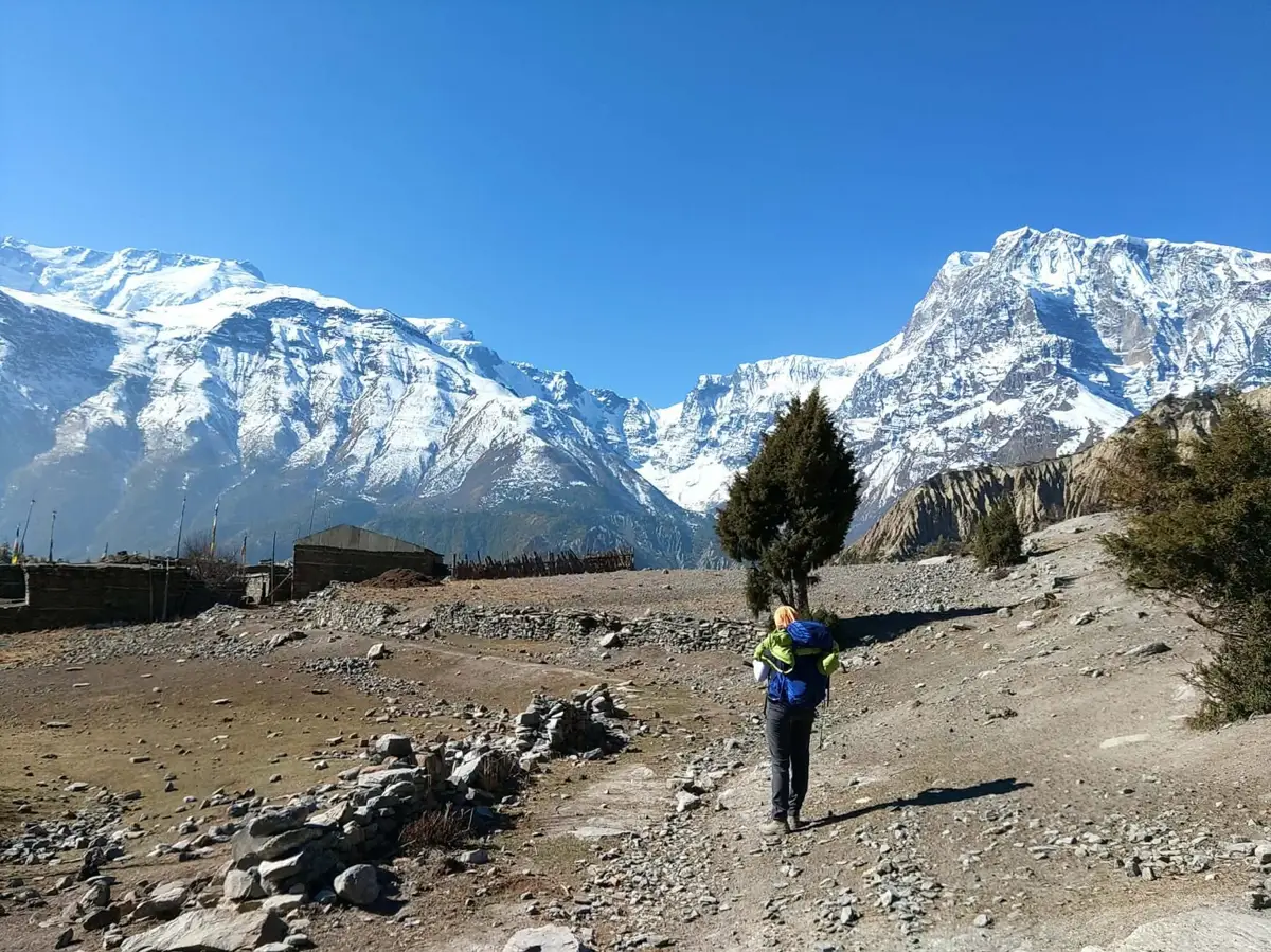 Laura marche seule avec son sac à dos vers les sommets enneigés