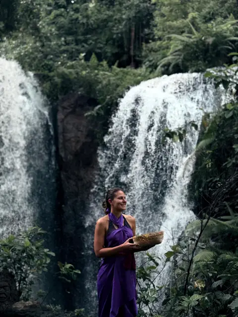 Laura avec une offrande devant une cascade à Bali