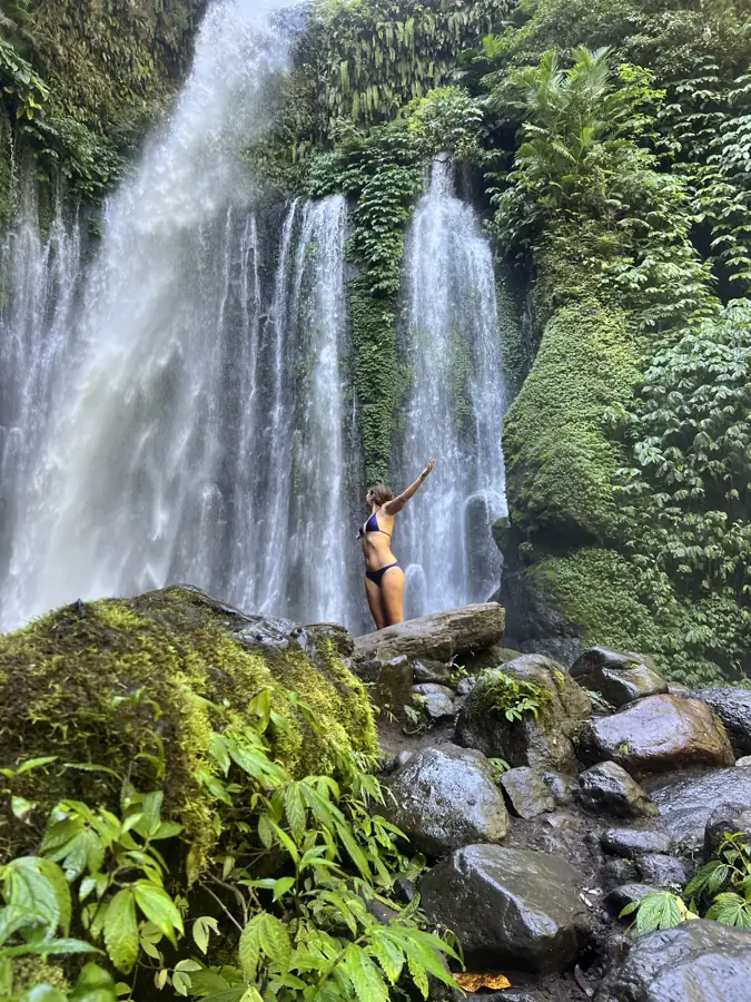 Laura les bras ouverts devant une cascade en Indonésie